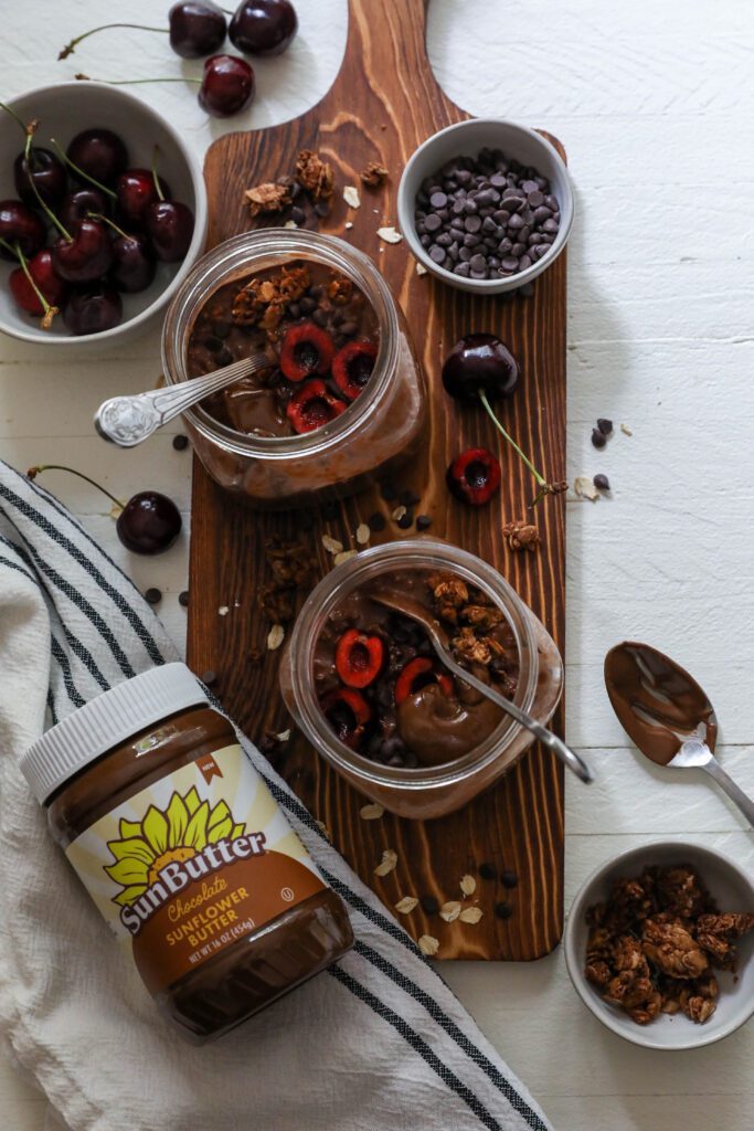 Chocolate Cherry Overnight Oats served in mason jars with spoons topped with cherries and chocolate chips 