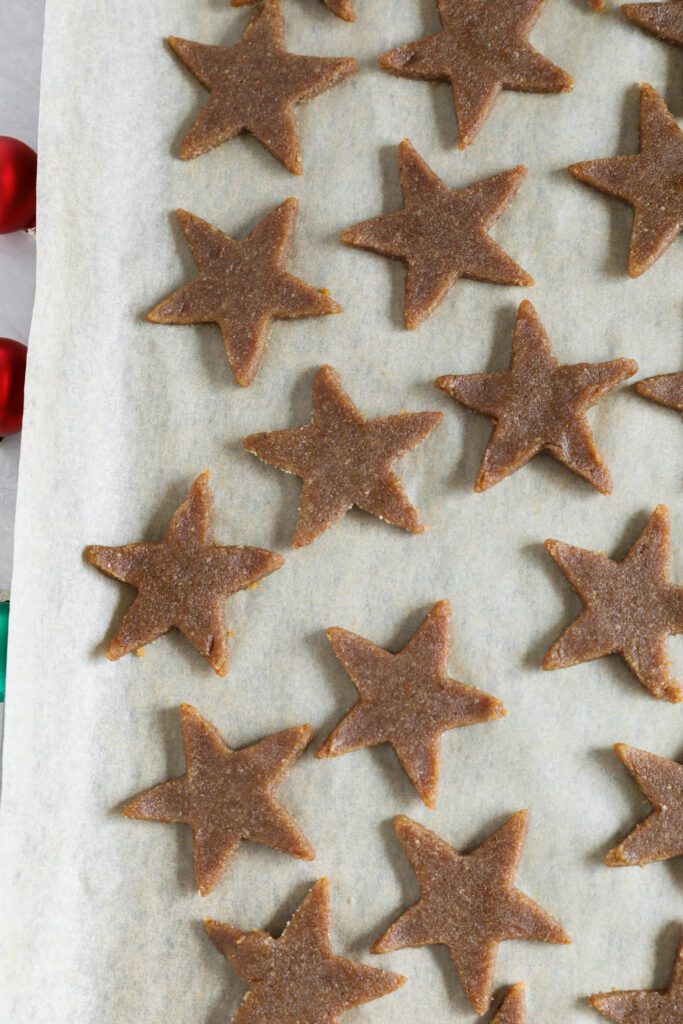 Cinnamon SunButter Star Cookies (Zimtsterne) cut into stars on parchment paper by Flora & Vino