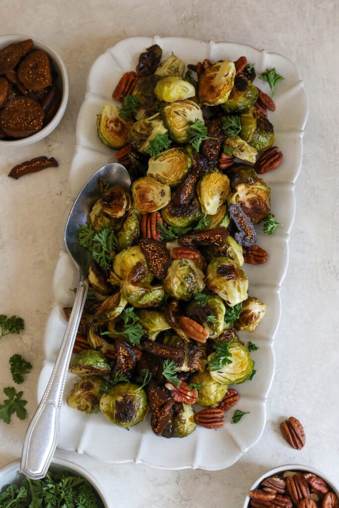Roasted Brussels Sprouts with Figs & Pecans served on dish with spoon by Flora & Vino