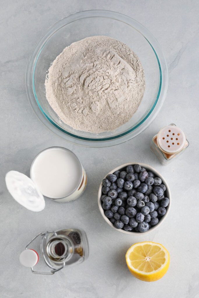 Blueberry Buckwheat Pancake ingredients on wooden board with blueberries and lemon by Flora & Vino