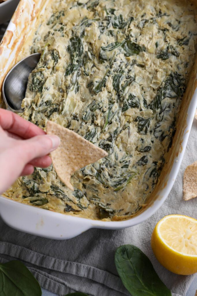 Spinach Artichoke Cashew Dip with chip dipping by Flora & Vino