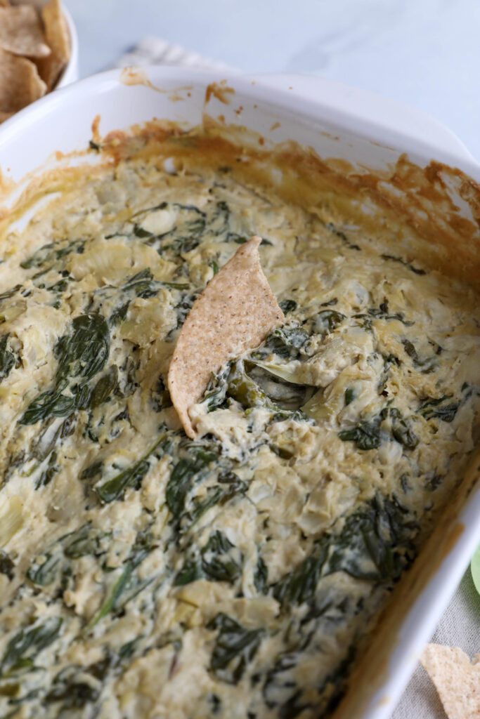 chip dipped in Spinach Artichoke Cashew Dip by Flora & Vino