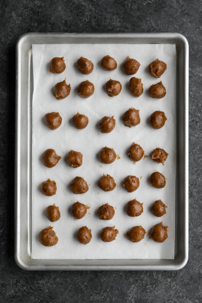 caramel filling rolled into balls on parchment lined baking sheet by Flora & Vino