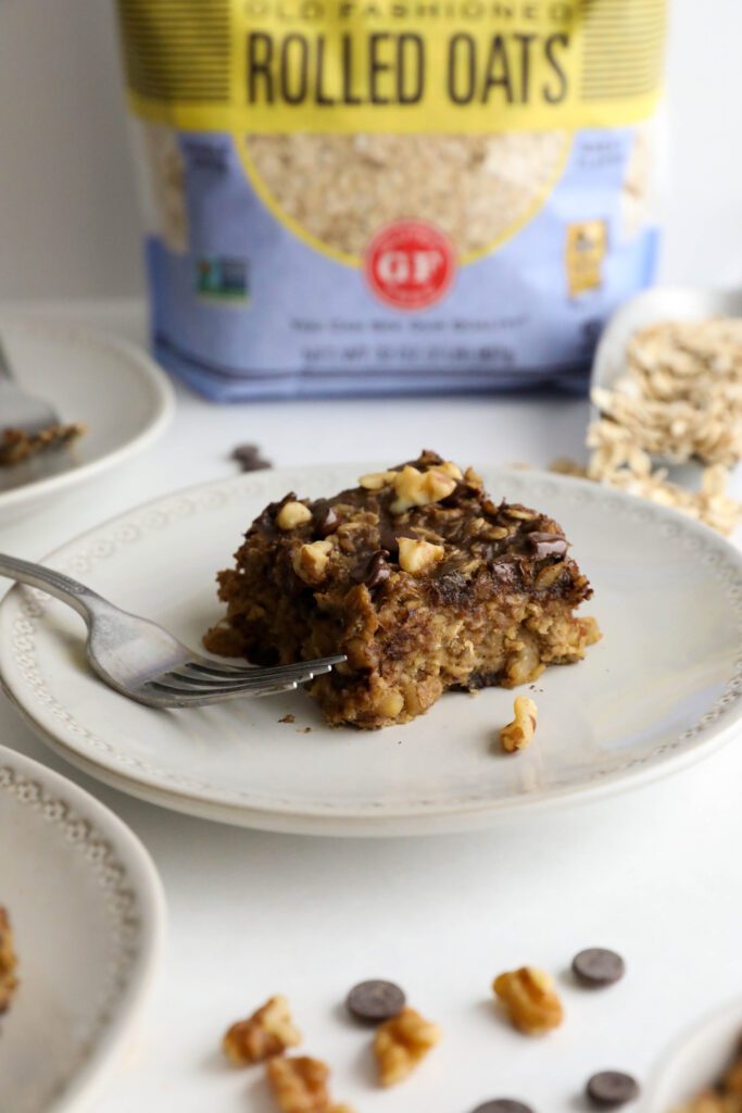 Banana Oatmeal Chocolate Chip Breakfast Bars served on plates with two forks with oatmeal, chocolate chips, and walnuts scattered