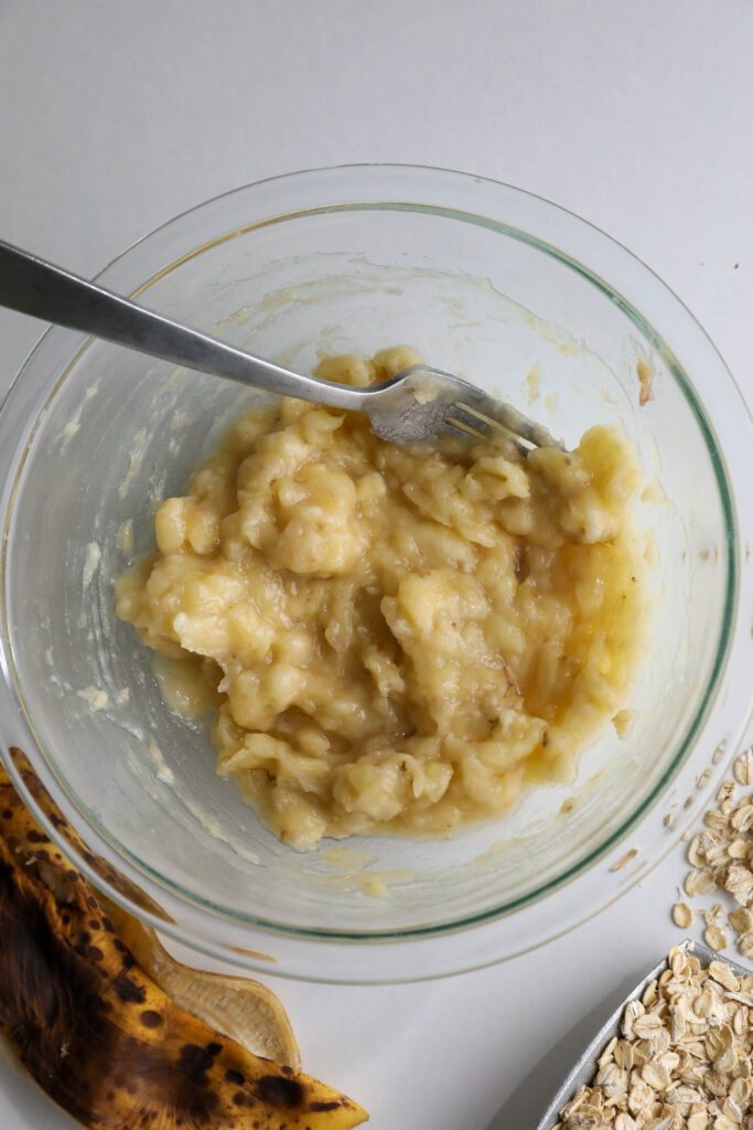 banana mashed in glass bowl with fork 