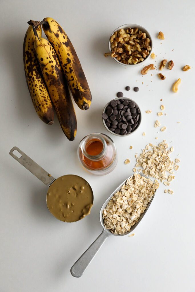 oats, dark chocolate chips, walnuts, nut butter, banana, and maple syrup on white board
