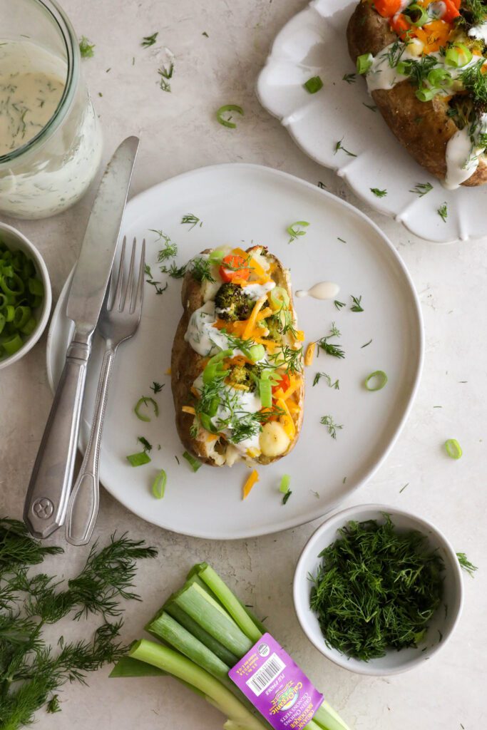 Veggie Loaded Twice Baked Potato served on a plate topped with fresh dill and green onion and fork and knife