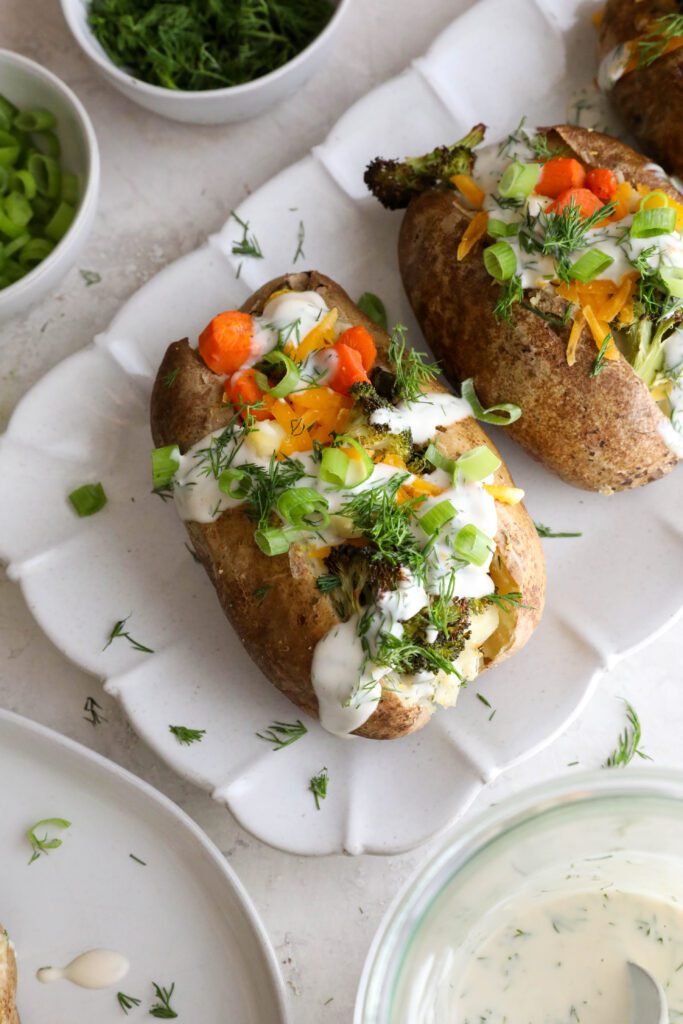 Veggie Loaded Twice Baked Potato served on a platter topped with fresh dill and green onion and fork and knife