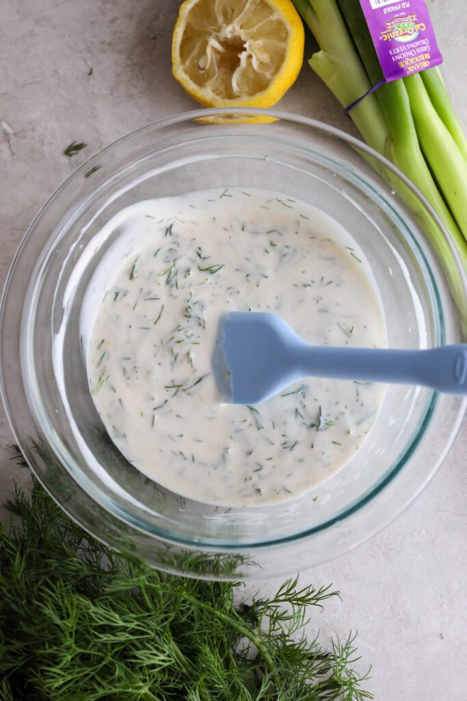 yogurt dill sauce mixed in bowl with spatula 