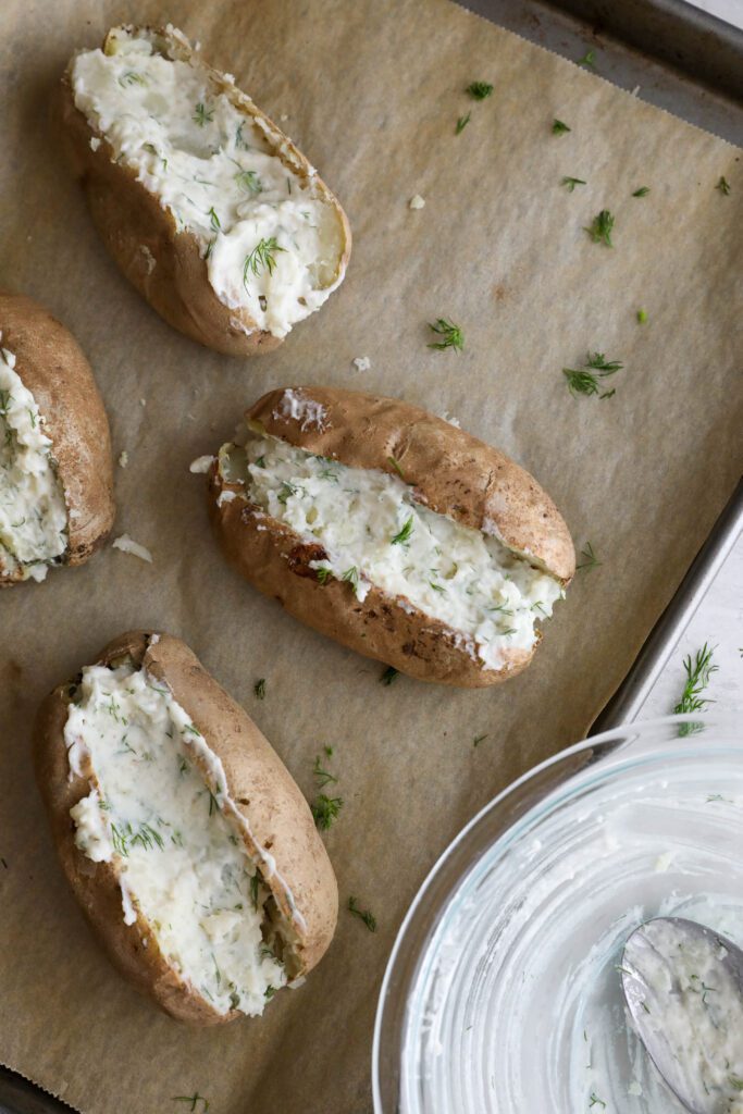 russet potatoes stuffed with yogurt dill sauce and potato filling on parchment lined baking sheet