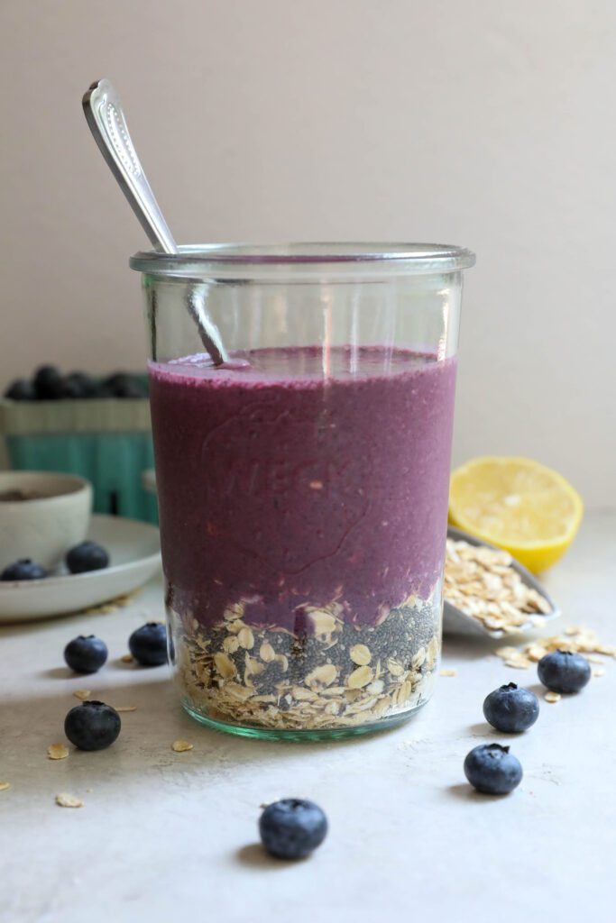 Blueberry Protein Overnight Oats ingredients in mason jar with a spoon by Flora & Vino