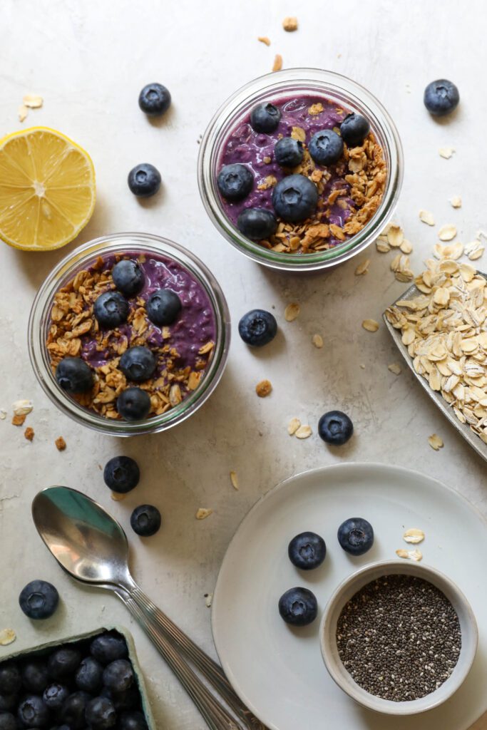 Blueberry Protein Overnight Oats served in mason jars with blueberries and granola by Flora & Vino