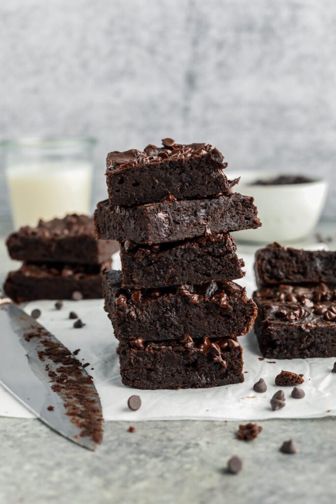 Flourless Vegan Brownies stacked with chocolate chips and knife by Flora & Vino 