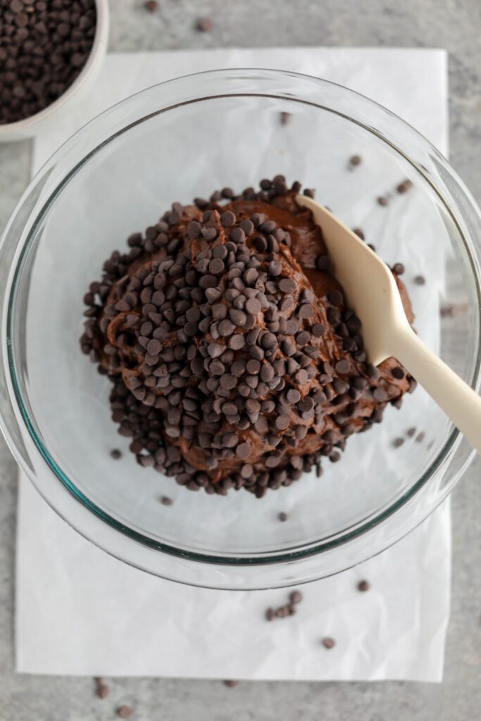 Brownie batter with chocolate chips in glass bowl with spatula by Flora & Vino