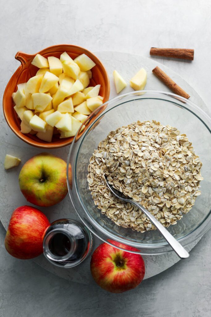 oats, apples, and cinnamon on wooden board by Flora & Vino