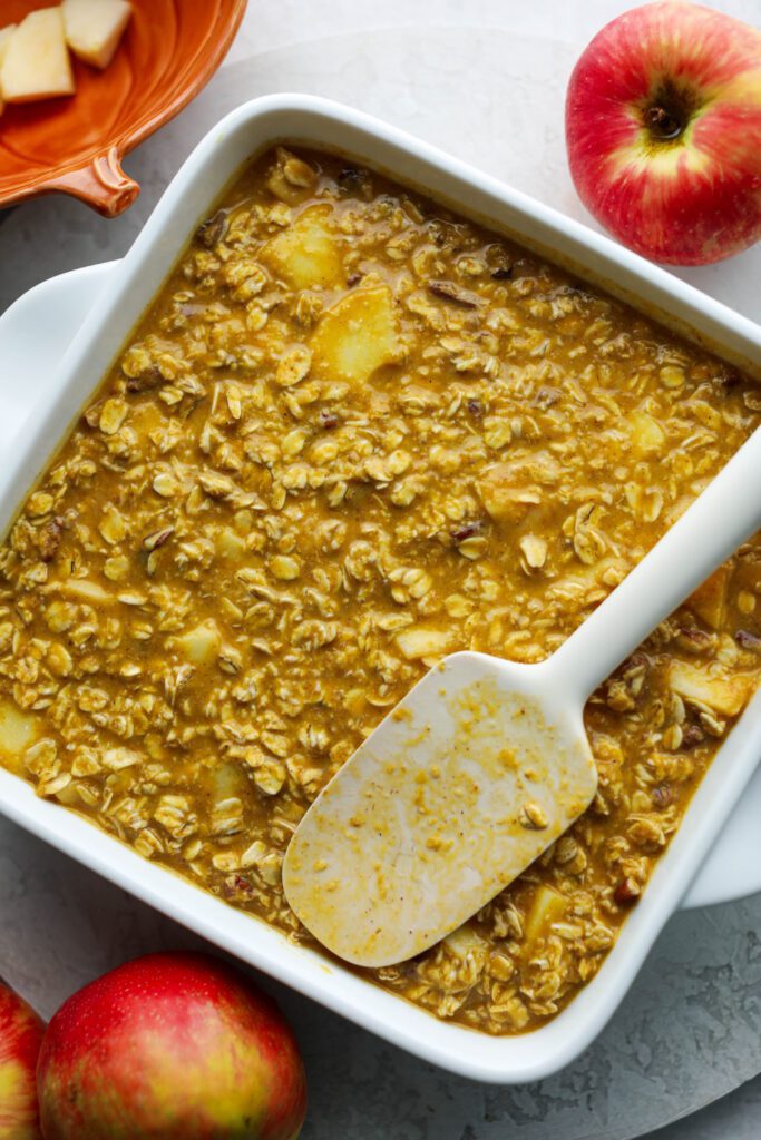 Pumpkin Apple Baked Oatmeal in square baking dish with spatula by Flora & Vino