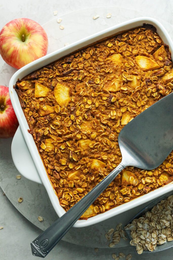 Pumpkin Apple Baked Oatmeal in square baking dish with pie server by Flora & Vino