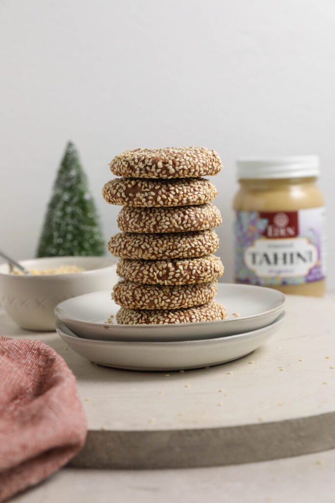 Chocolate Sesame Tahini Cookies stacked on two plates with Eden Foods Tahini and sesame seeds in background by Flora & Vino 