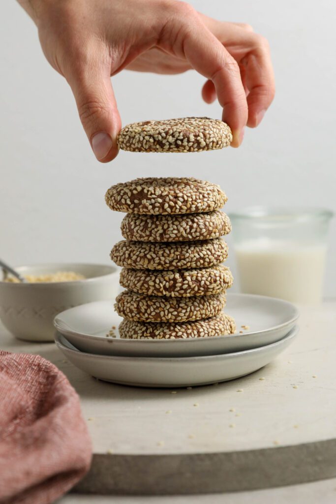 hand grabbing Chocolate Sesame Tahini Cookie from plates by Flora & Vino