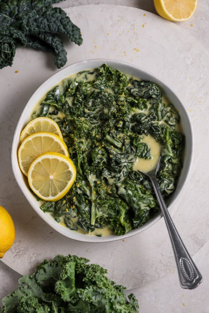 Coconut Creamed Kale served in bowl with spoon and lemons by Flora & Vino 