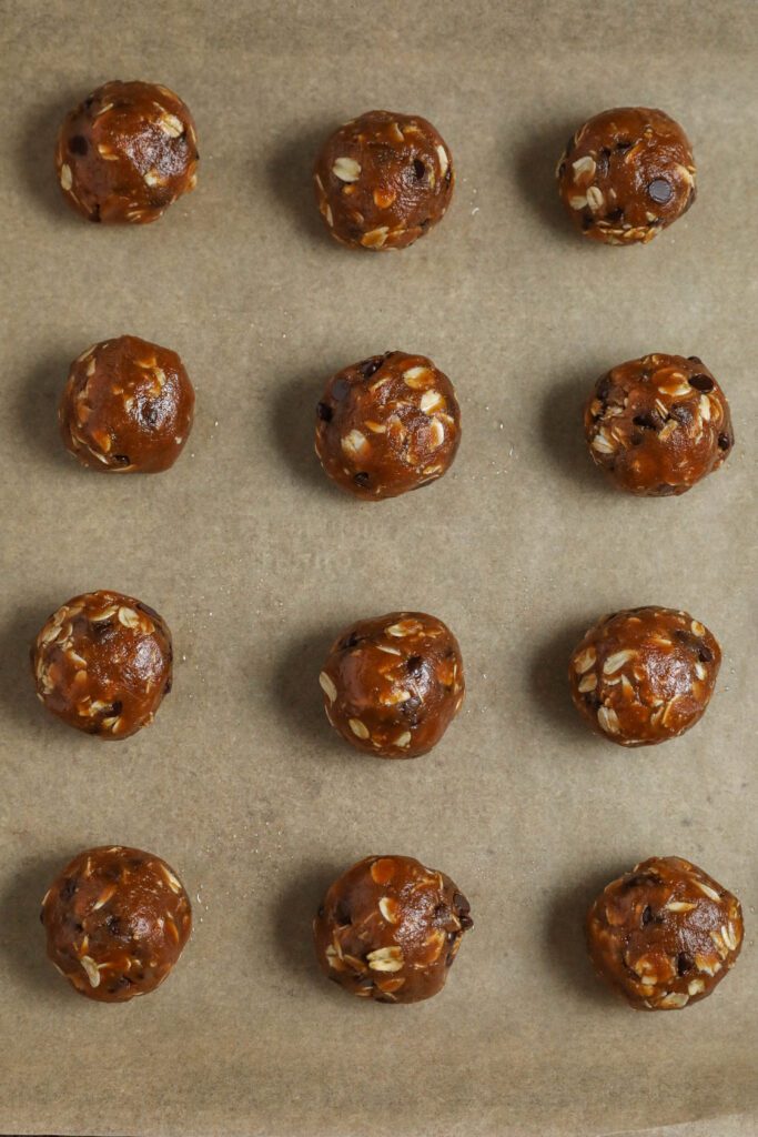 Peanut Butter Chocolate Chip Oatmeal Cookie Dough balls on parchment lined baking sheet by Flora & Vino