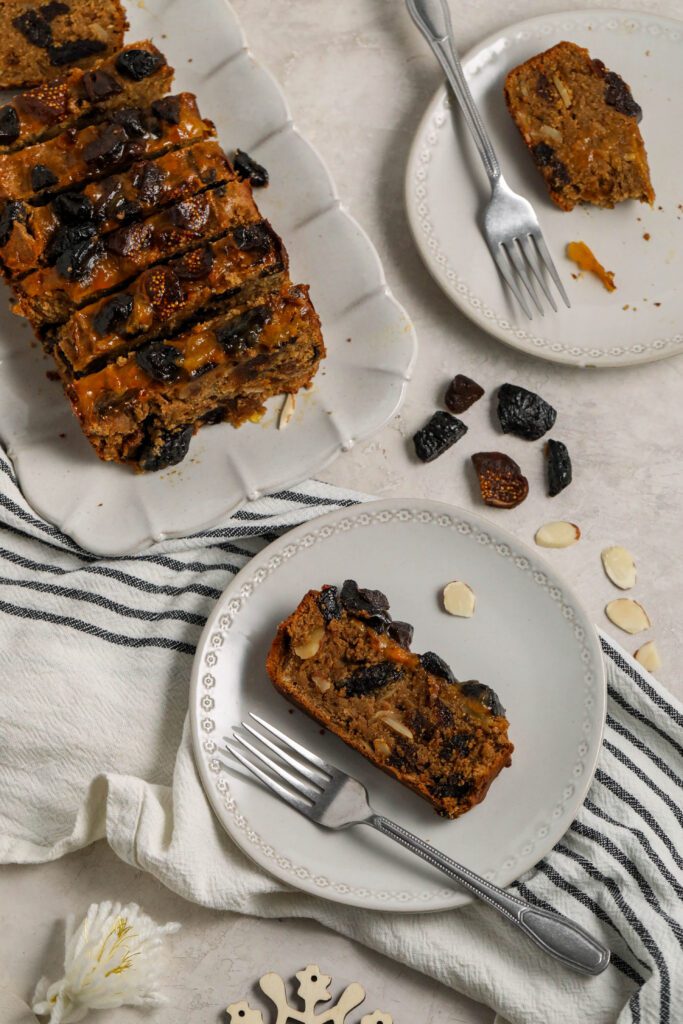 Vegan Holiday Fruit Cake sliced and served on plates with forks by Flora & Vino