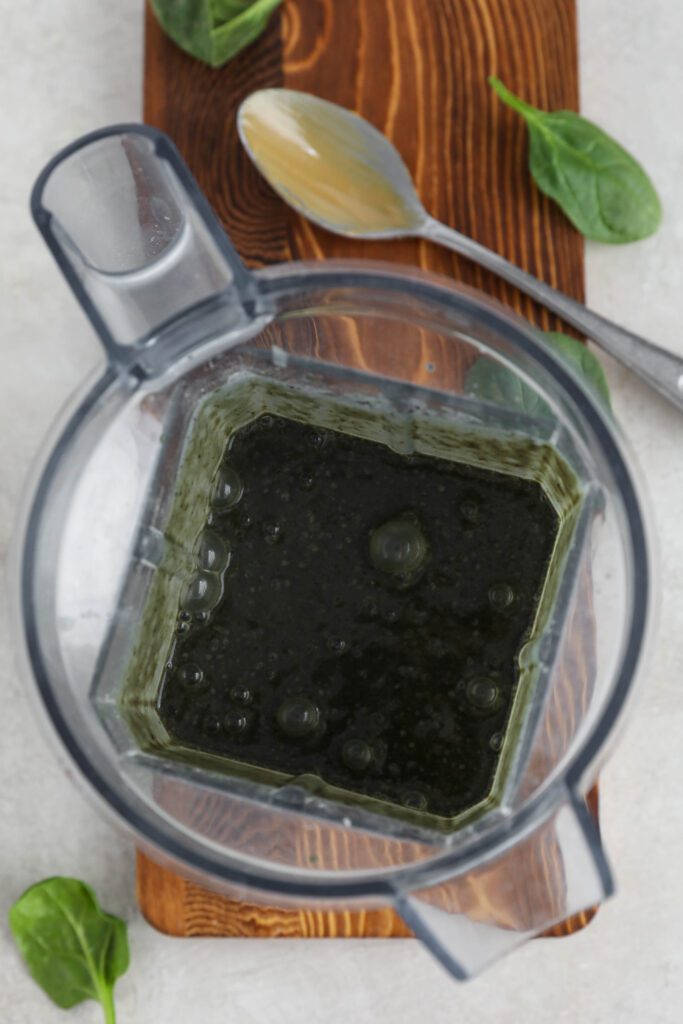 My Go-To Green Smoothie blended in Vitamix on wooden board with spinach leaves and spoon by Flora & Vino