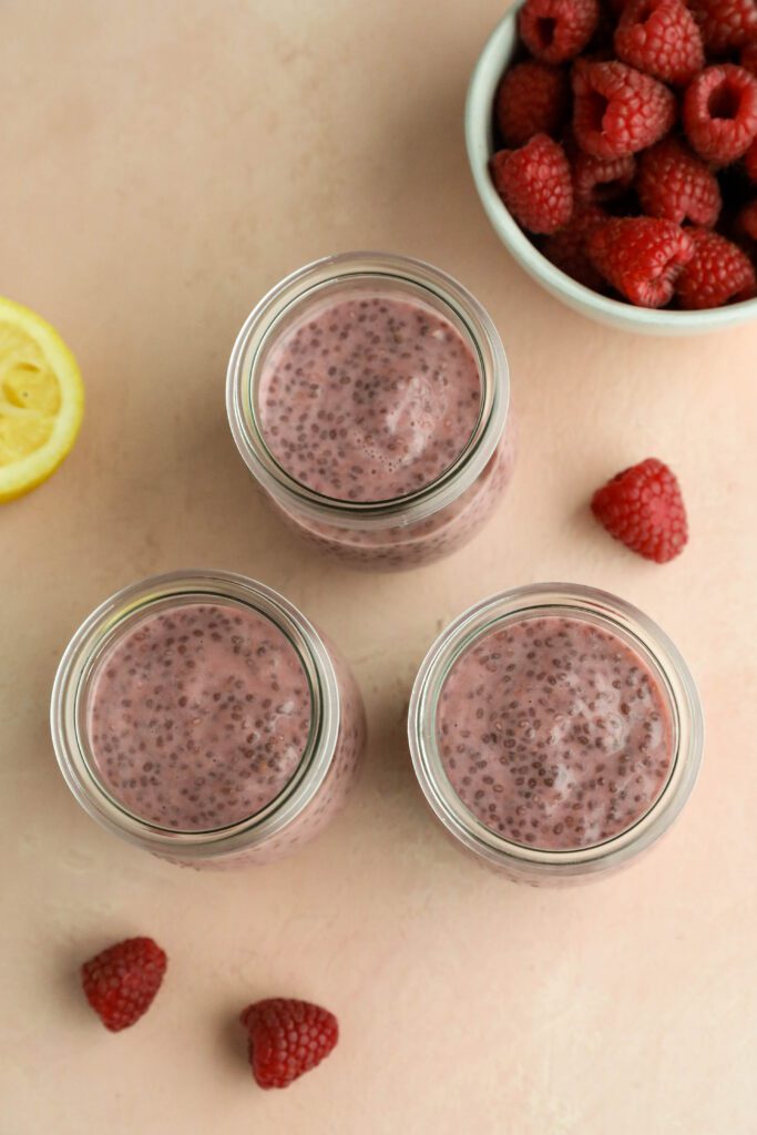 Raspberry Chia Pudding served in mason jars with a bowl of fresh raspberries and half a lemon on the side by Flora & Vino