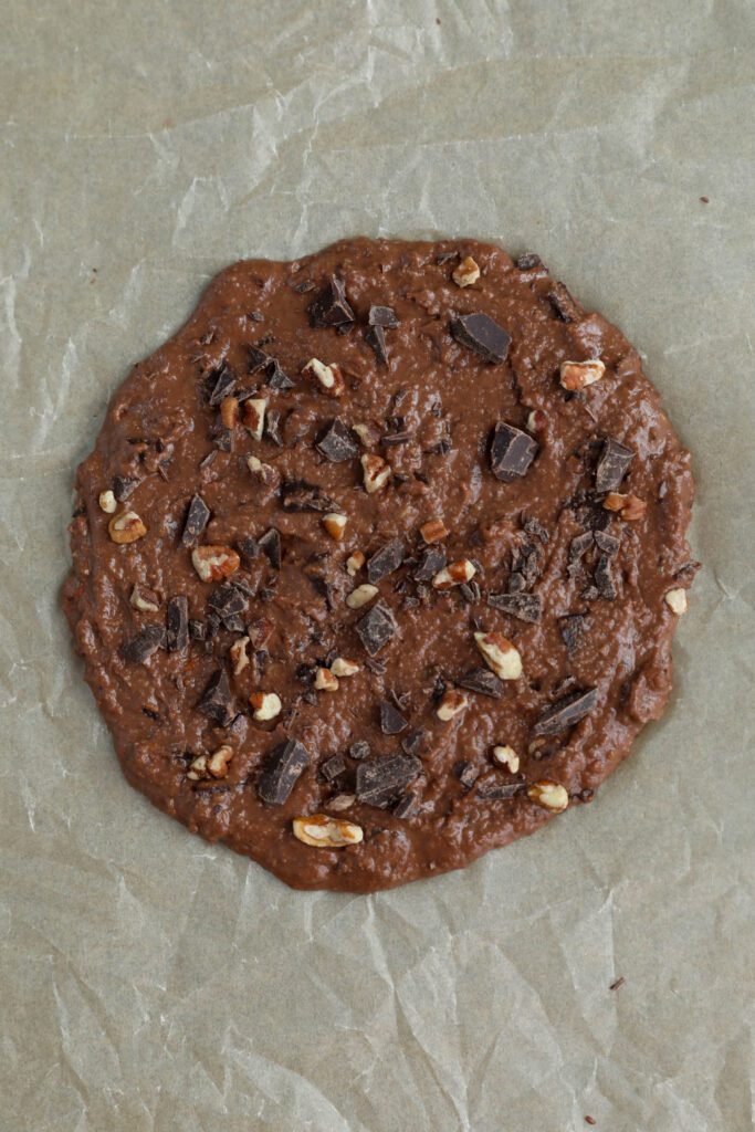 Single Serve Double Chocolate Chunk Cookie formed into a large circle on parchment lined baking sheet by Flora & Vino 