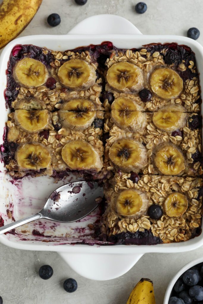 Blueberry Banana Baked Oatmeal baked in square baking dish and sliced into six pieces with one piece missing by Flora & Vino