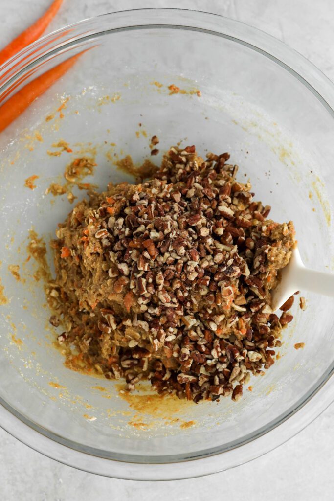 carrot cake cookies batter mixed with spatula with chopped pecans on top by Flora & vino