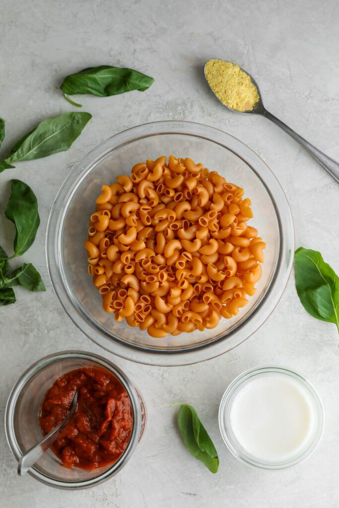 chickpea pasta, marinara sauce, almond milk, basil, and nutritional yeast on wooden board by Flora & Vino