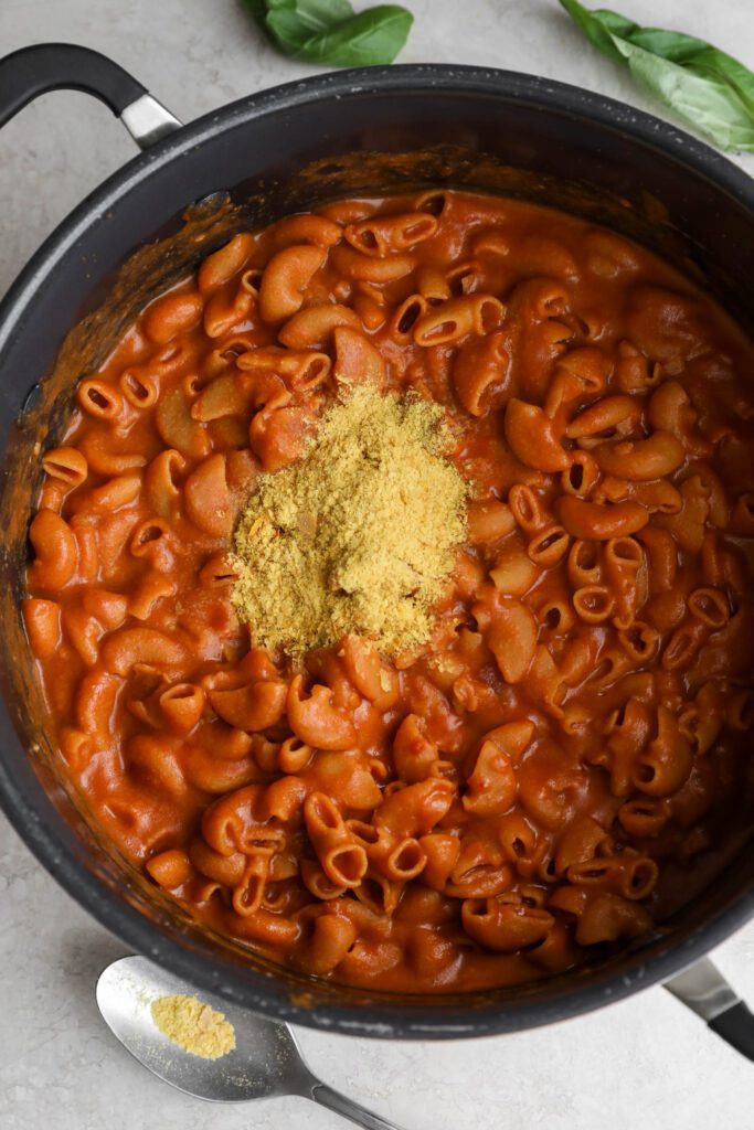 Creamy Vegan 1-Pot Pasta in stockpot with a spoonful of nutritional yeast by Flora & Vino