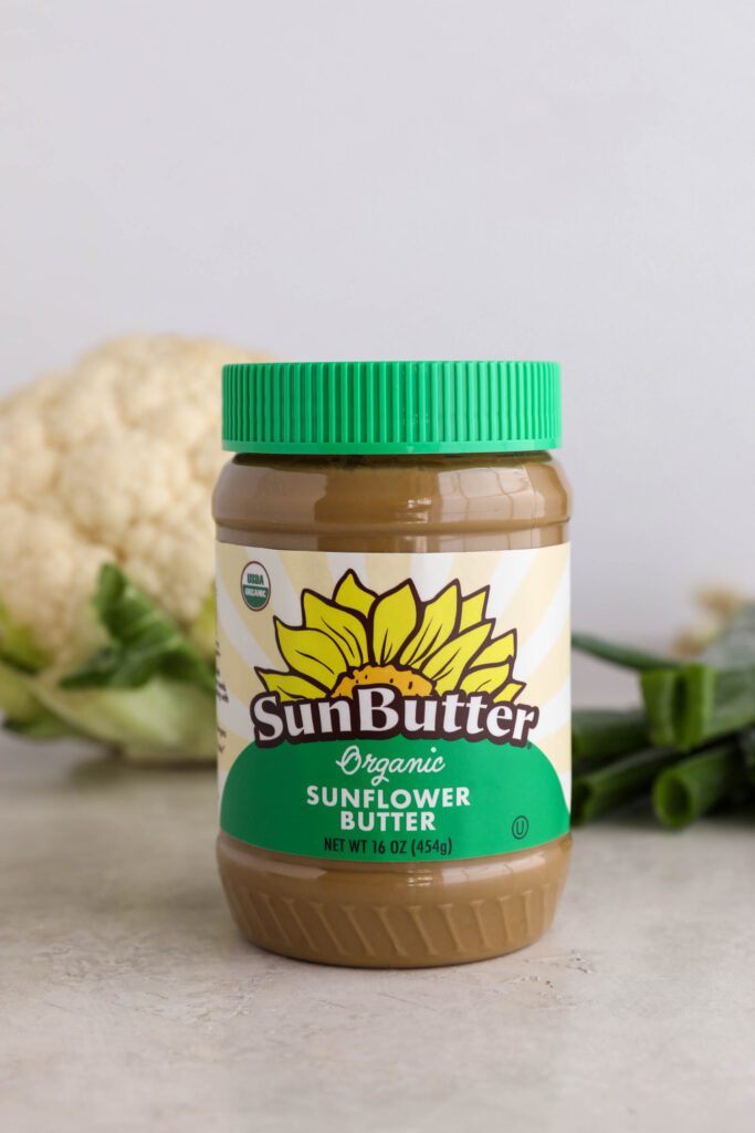 Organic SunButter with head of cauliflower and green onion behind the jar by Flora & Vino