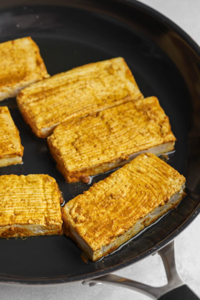 tofu rectangles covered in marinade in pan by Flora & Vino