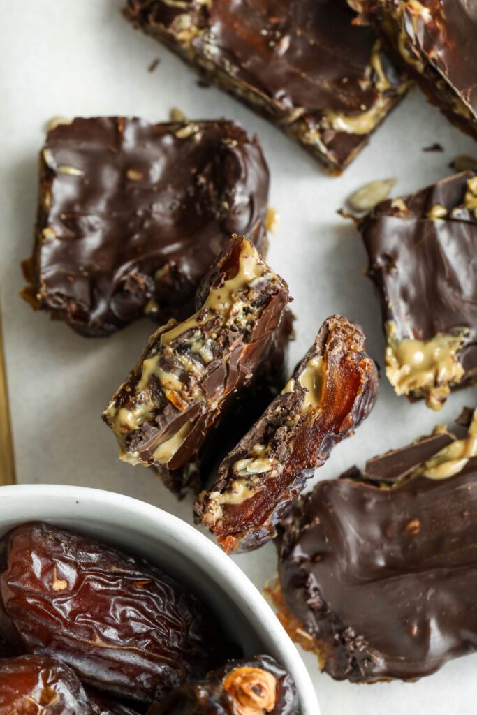 Viral Date Bark (Nut-Free!) cut into squares and served on parchment lined wooden board by Flora & Vino