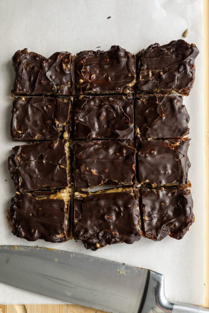 Viral Date Bark (Nut-Free!) cut into squares and served on parchment lined wooden board by Flora & Vino