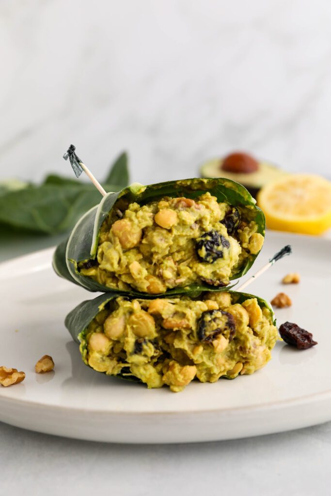 Curried Chickpea Salad Collard Wraps halved on plate with half a lemon and avocado in the background