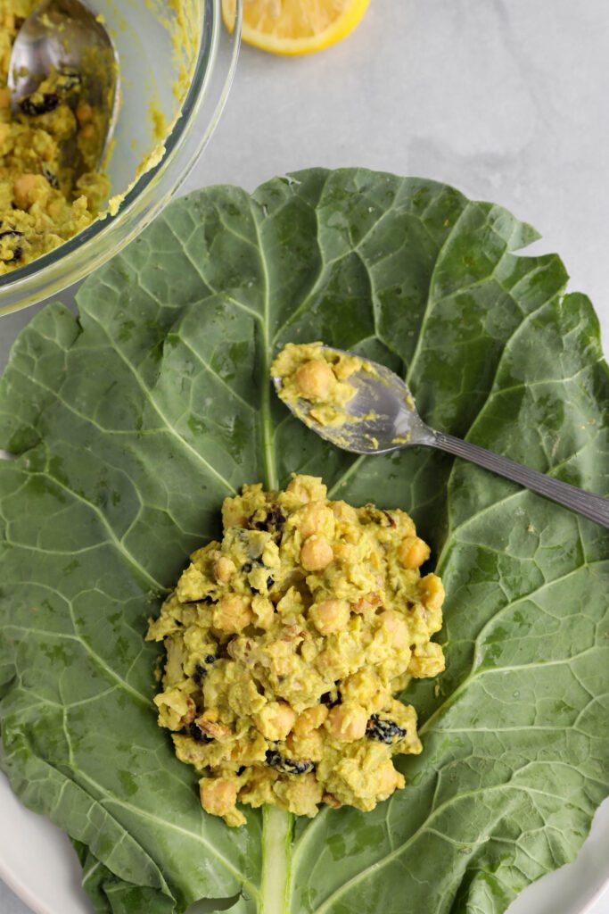 Curried Chickpea Salad added to collard leaf with a spoon 