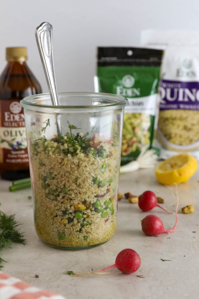 two Spring Quinoa Salad Jar mixed together with spoon in jar and pistachios, radishes, dill, lemon, and green onion on the side