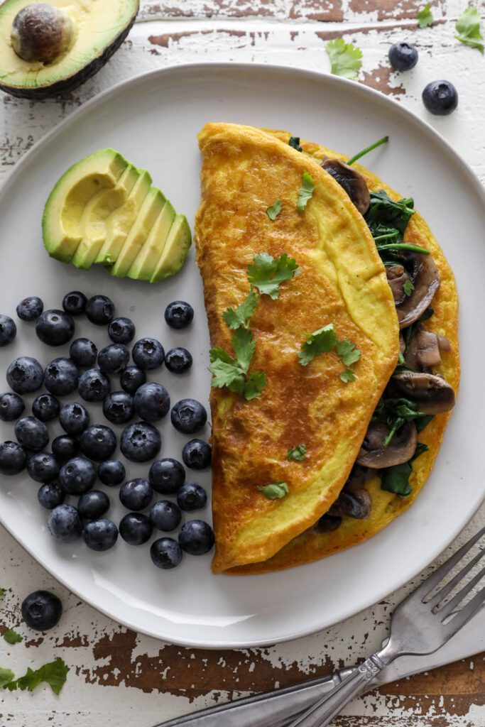 Vegan Mushroom Omelette served on plate with blueberries and avocado topped with cilantro 