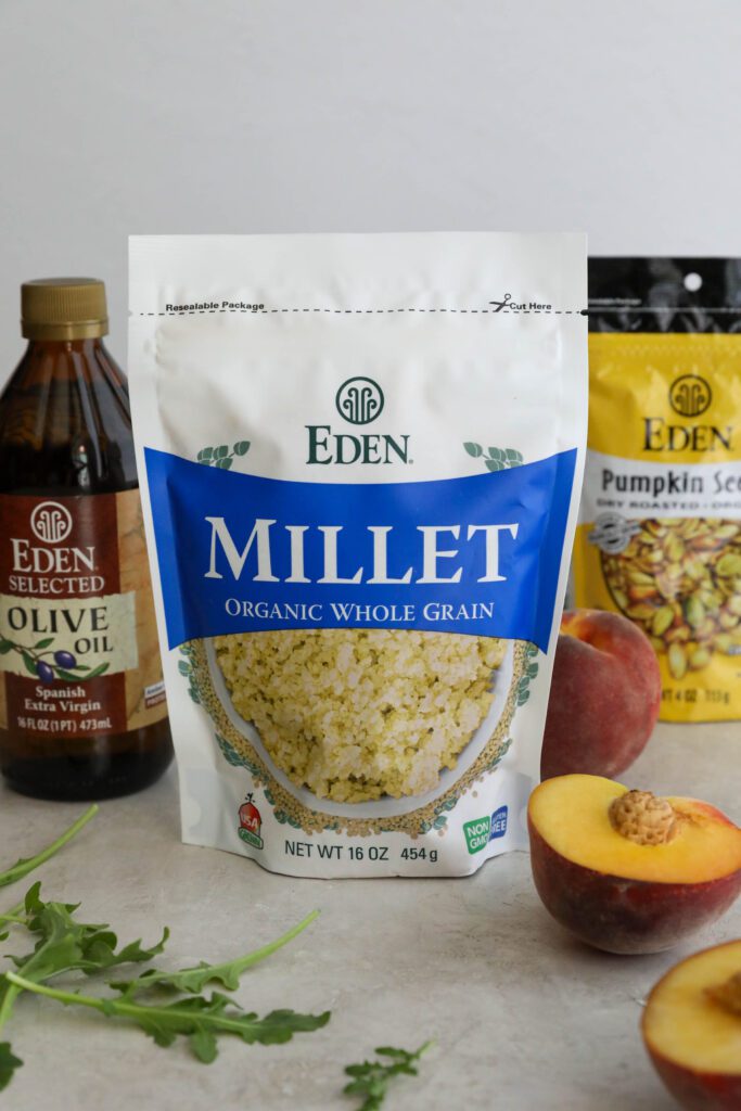 Eden Foods Millet, Eden Foods Olive Oil, and Eden Foods Pumpkin Seeds in packaging with arugula and peaches