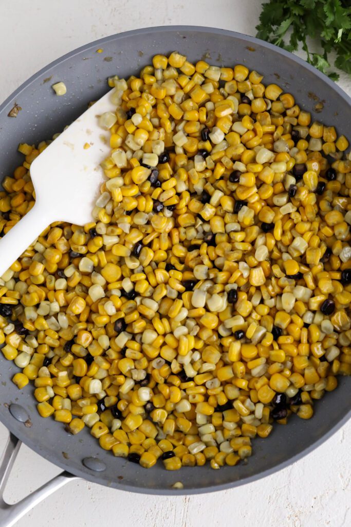 frozen corn heated in pan with spatula 