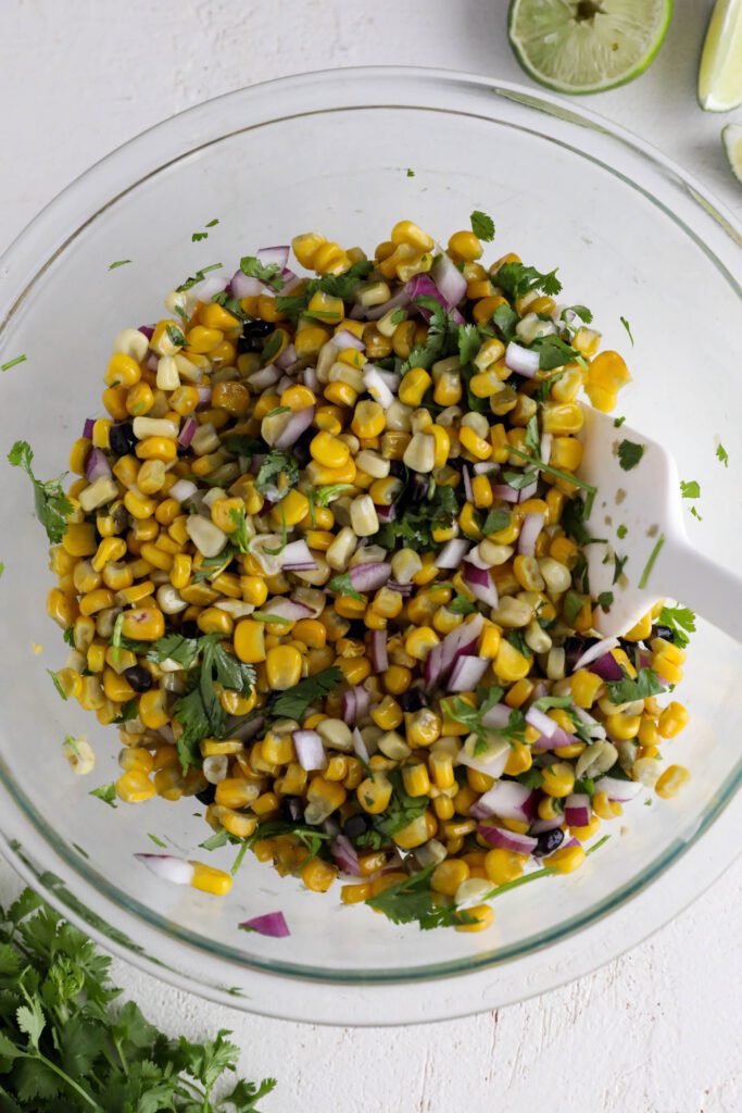 cooked corn, red onion, and cilantro mixed in bowl