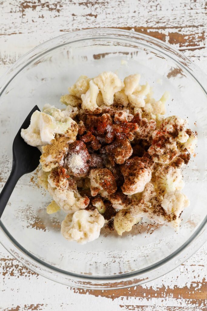frozen cauliflower in bowl topped with spiced with spatula 