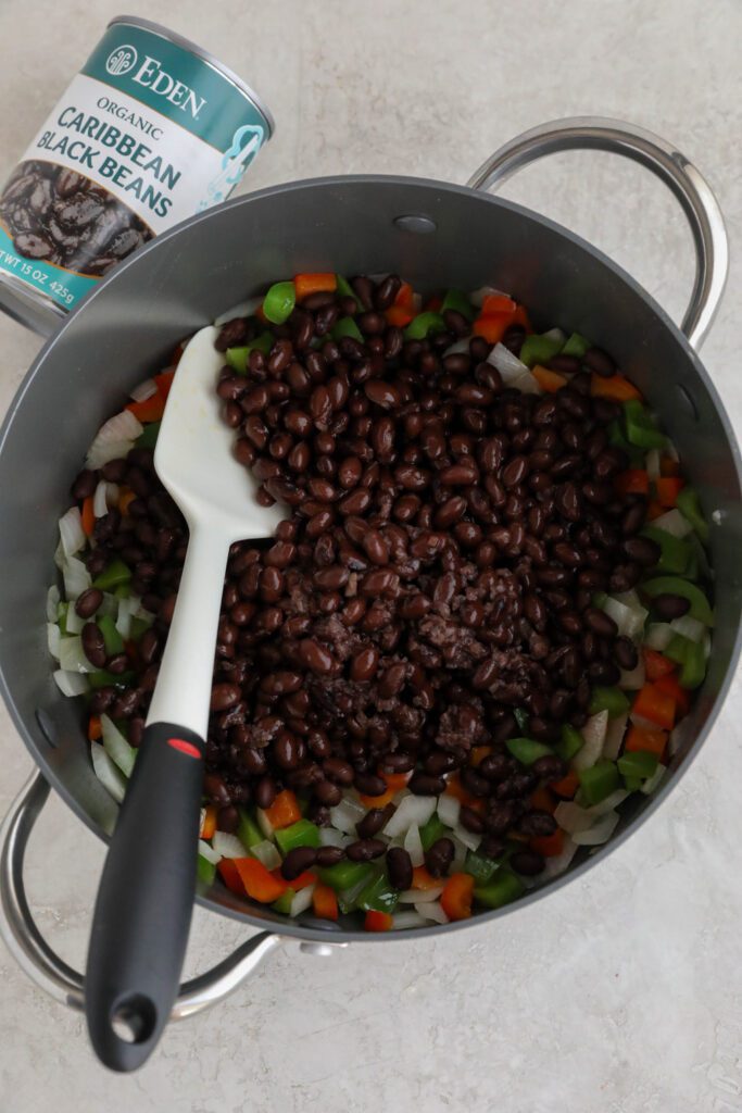 Caribbean Black Beans with sauteed peppers and onionsin pot with spatula 