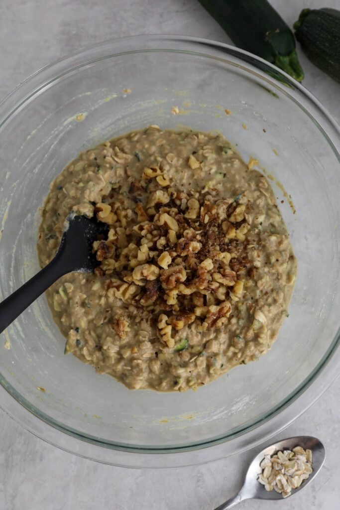 Vegan Zucchini Bread batter mixed with spatula and chopped walnuts on top 