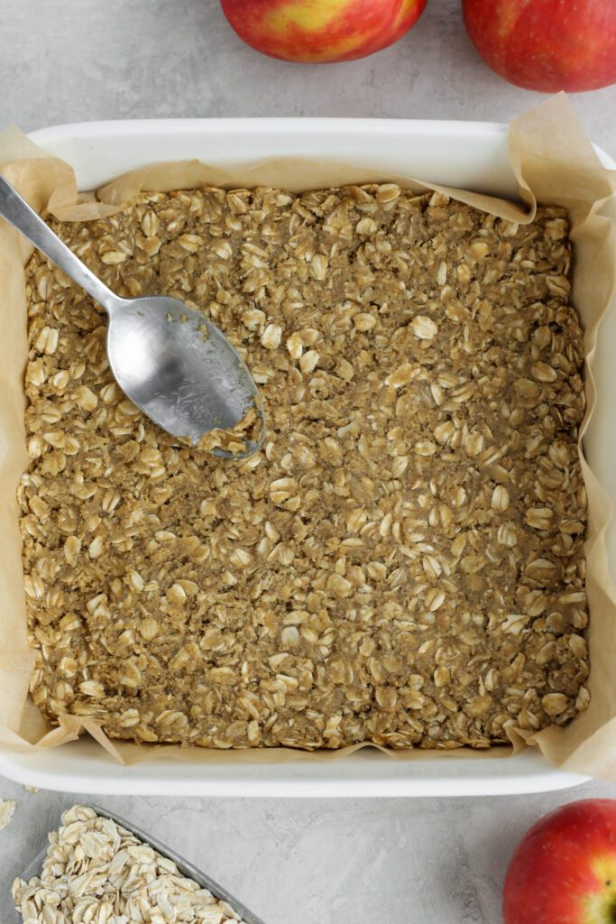 crust spread into parchment lined baking dish with spoon and apples and oats