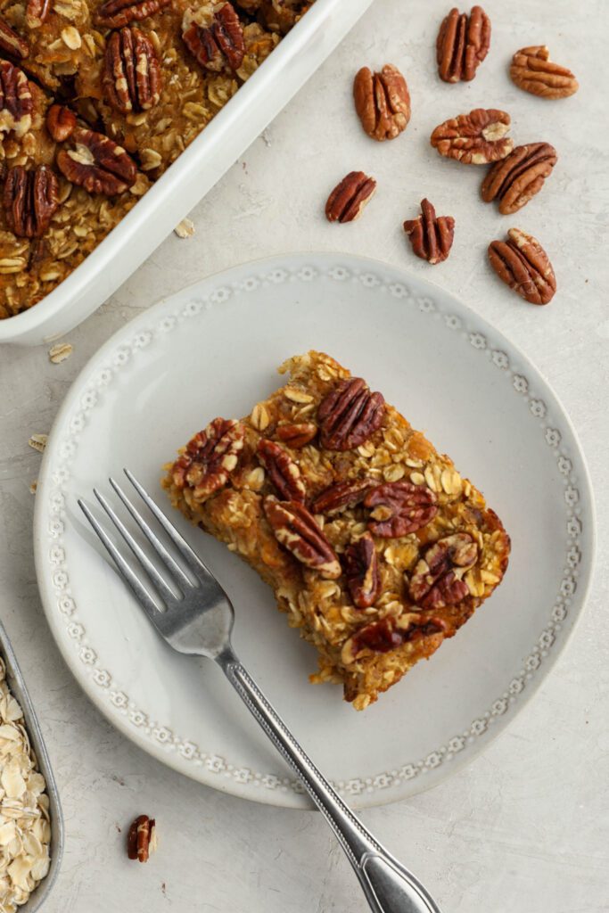 Sweet Potato Pie Baked Oatmeal served in casserole dish with pie server with pecans and oats 