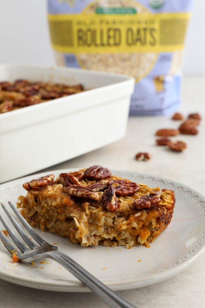 Sweet Potato Pie Baked Oatmeal served in casserole dish with pie server with pecans and oats 